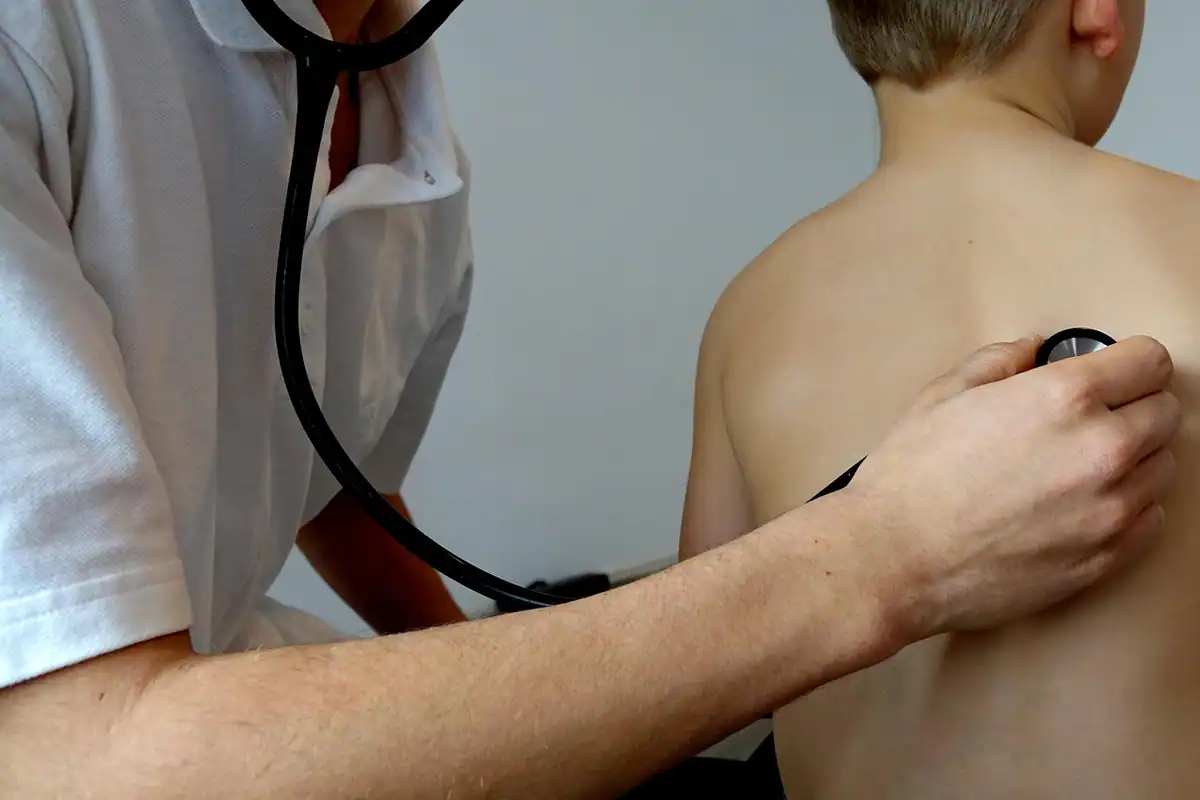 Medic care ascultă cu stetoscopul spatele unui copil în timpul unui consult