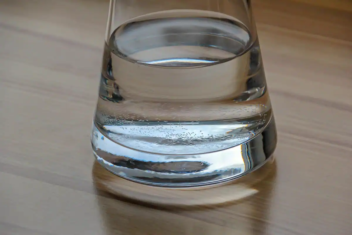 Carafă transparentă cu apă, pe o masă din lemn, pentru hidratare