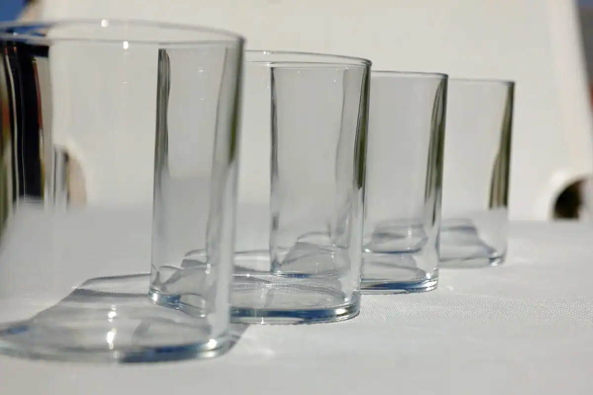 Pahare transparente goale aliniate pe o masă albă, pentru apa băută înainte de ecografie