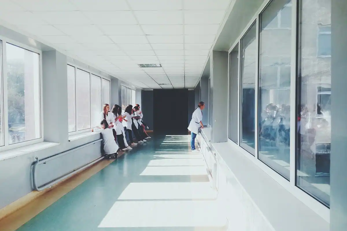 Coridor luminos de spital cu ferestre mari și personal medical în depărtare