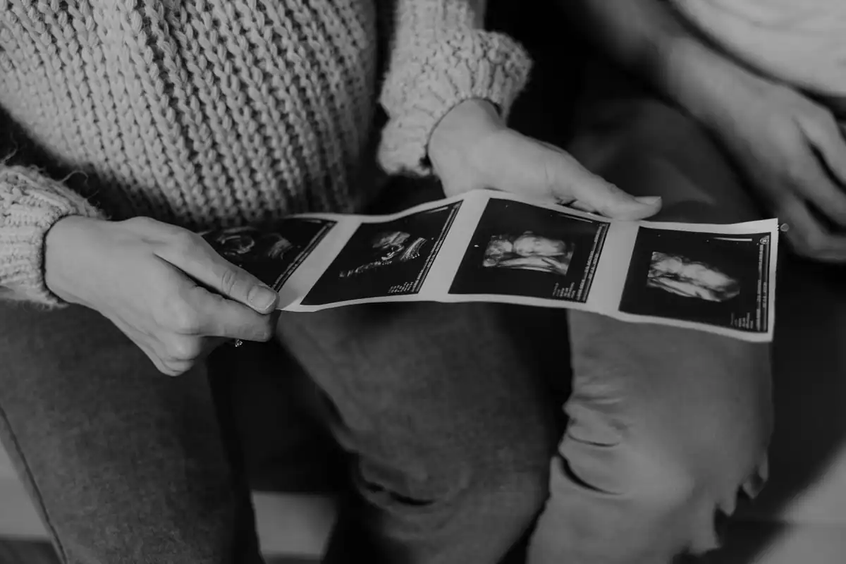 Părinți care țin în mâini fotografii de ecografie, citind imaginile împreună